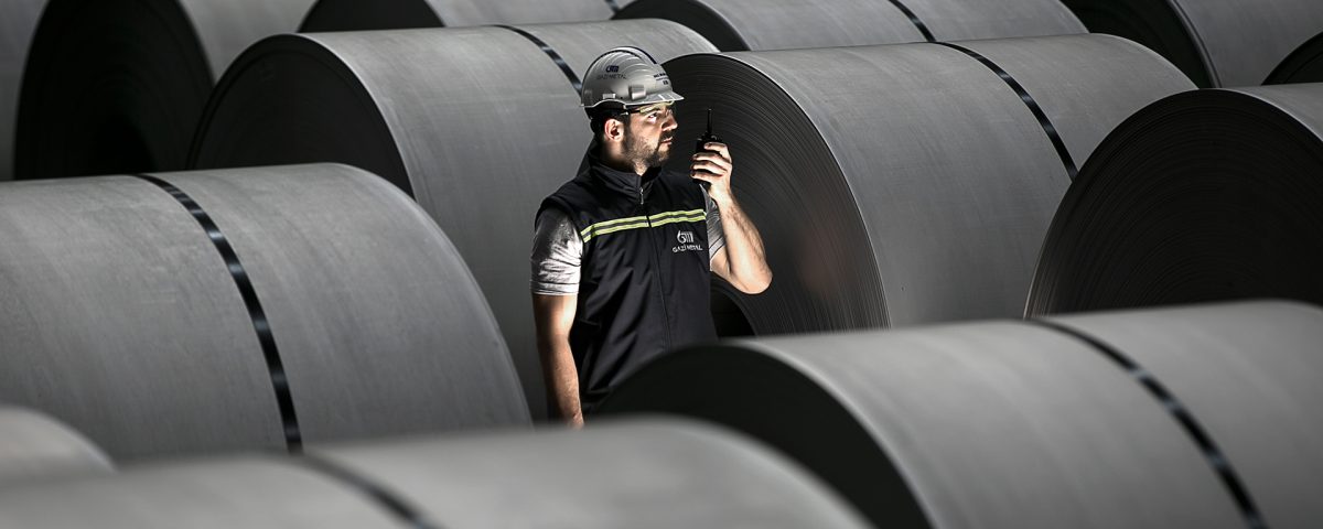 Gazi Metal employee inspecting steel coils in a modern industrial metal production facility.
